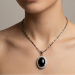Load image into Gallery viewer, Woman wearing a necklace with a black pendant on a neutral background