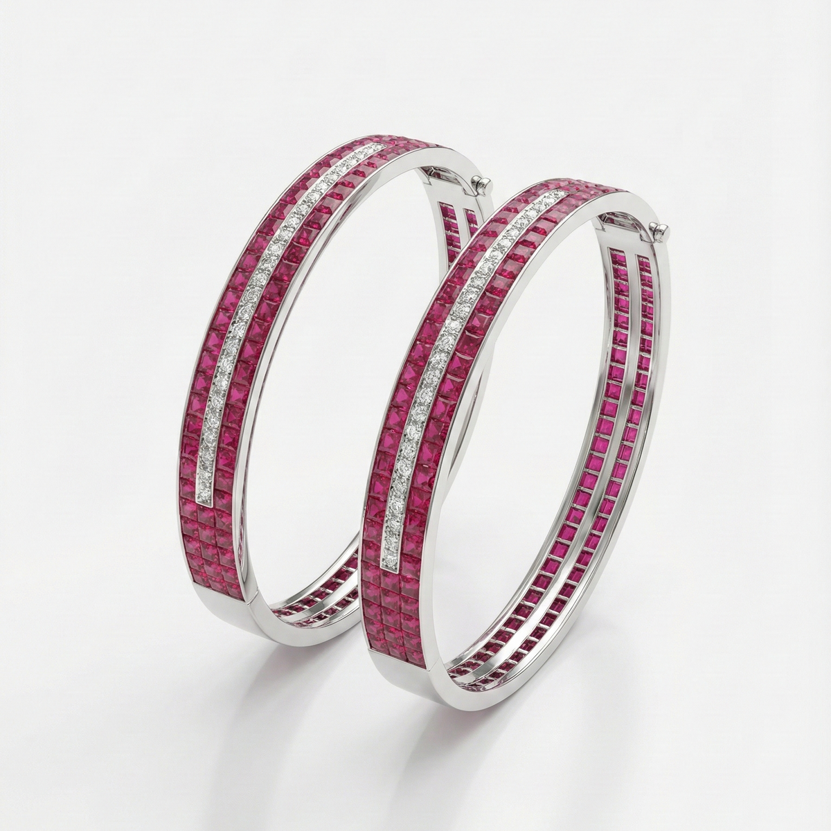 Pair of hoop bangles with pink gemstone and clear stones on a white background