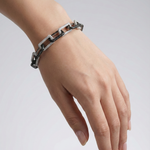 Load image into Gallery viewer, Hand wearing a silver chain bracelet on a light gray background
