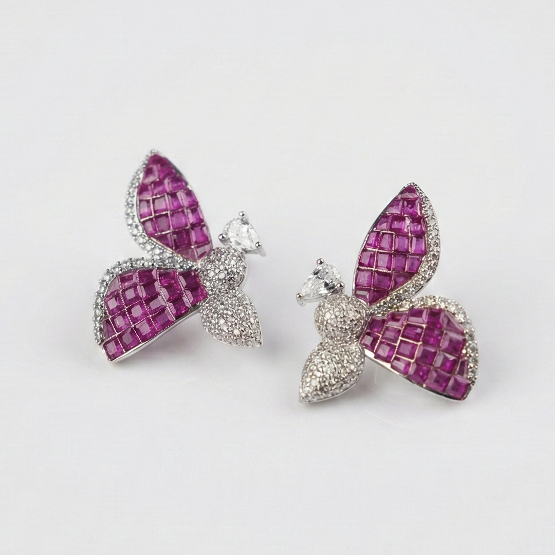 Butterfly-shaped earrings with pink and silver design on a light gray background