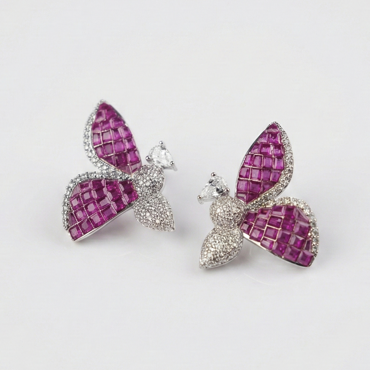 Butterfly shaped earrings with pink and silver design on a light gray background