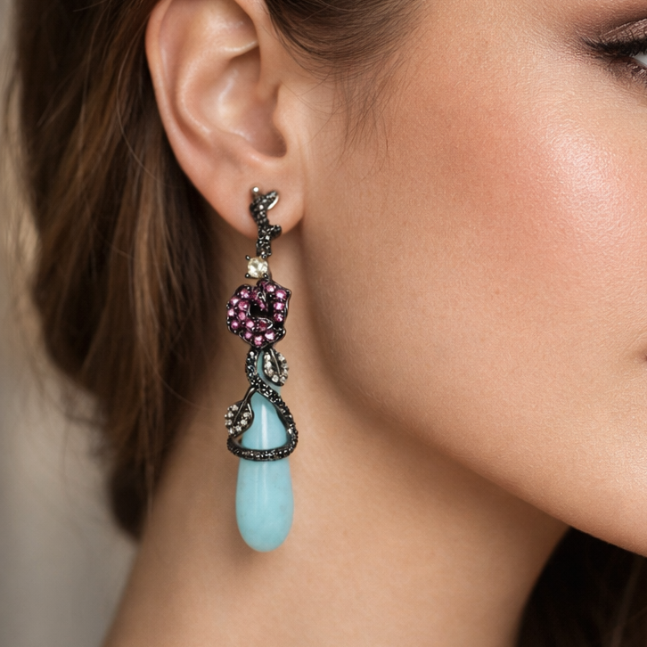 Close-up of a woman wearing a decorative earring with a blue teardrop and multicolored stones.