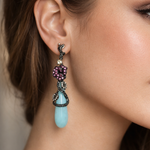 Load image into Gallery viewer, Close-up of a woman wearing a decorative earring with a blue teardrop and multicolored stones.
